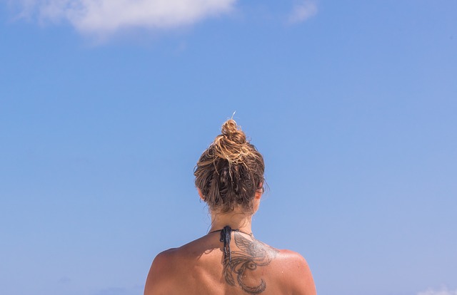 Žena otočená chrbtom, detail na jej krk s tetovaním.jpg